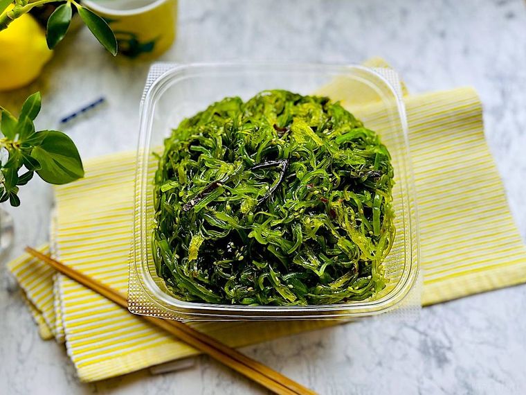 蓋を開けたコストコのごまわかめのパッケージ、イエローのランチョンマット、箸