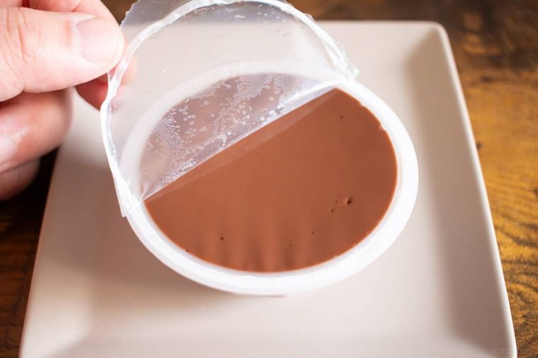 四角い白皿にのったふじや食品ショコラ胡麻どうふのカップを開けている様子