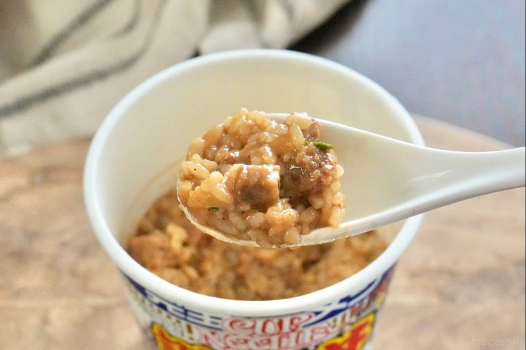 カップの謎肉丼を白いれんげですくう様子