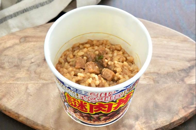 木のカッティングボードにのったカップの謎肉丼