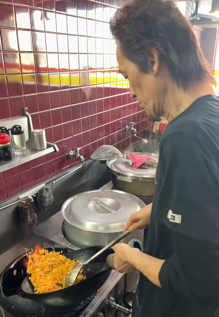 鍋を振るう濱井場さん