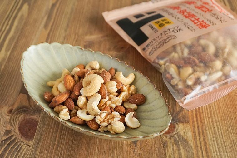 ミックスナッツが盛られた灰色の楕円の皿と素煎りミックスナッツDXのパッケージ