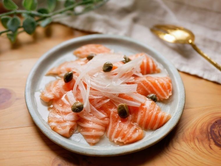 グレーの皿に盛り付けられたサーモンのカルパッチョ