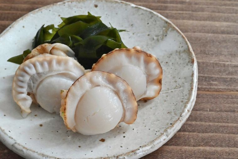 皿に盛られた3つのベビーホタテと添えられたわかめ