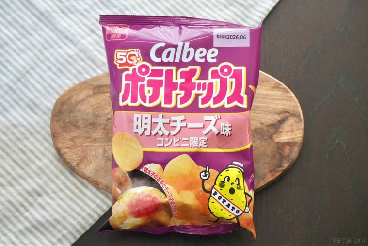 木のカッティングボードにのった紫色とピンク色のパッケージのポテトチップス