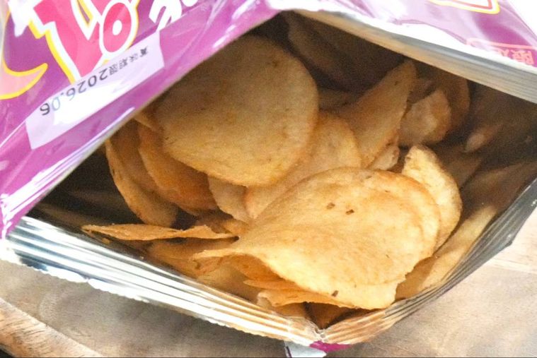 紫色とピンク色のパッケージのポテトチップスの袋を開けた様子