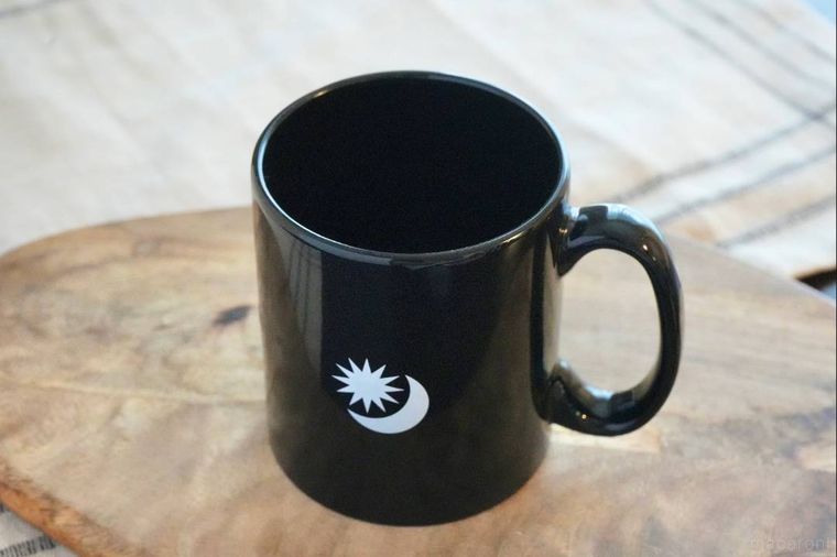 木のカッティングボードにのった黒色のマグカップ