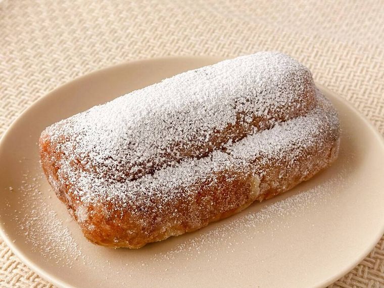 粉糖をふりかけたXmasスパイス香るシュトーレンが皿に盛り付けられている様子