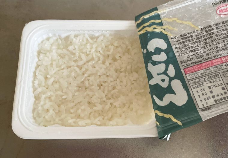 レンジ加熱後のパックご飯のフィルムをはがしている