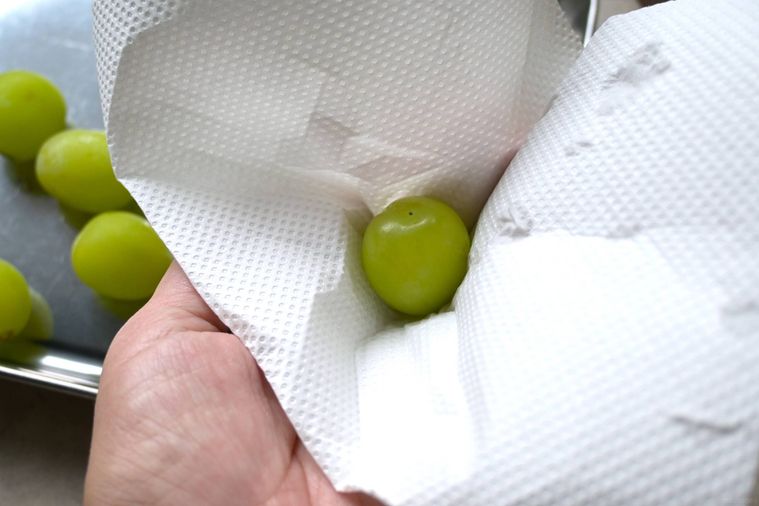 シャインマスカットの水気をキッチンペーパーでふき取る様子