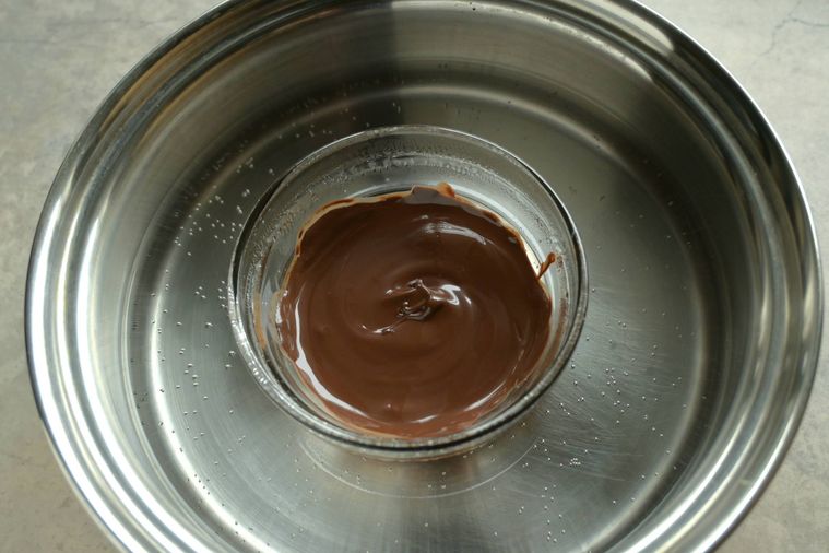 チョコレートが入ったガラスボウルの底を鍋の湯に当てる様子