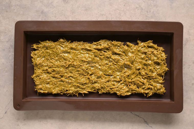 ピスタチオペーストとカダイフを混ぜたフィリングをチョコレート型に詰めた様子