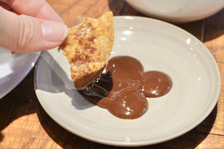 白い小皿の上で溶かしたクーベルチュールチョコレートを煎餅につける様子
