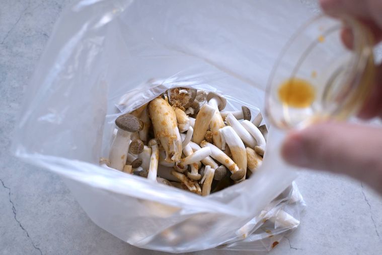 食品用ポリ袋に入れたしめじに調味料を加える様子