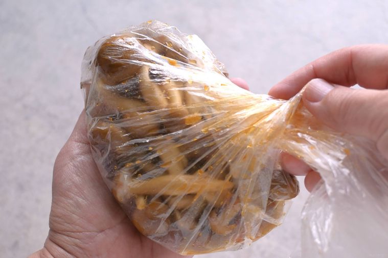 ポリ袋に入れたしめじを手で揉み、味付けをする様子