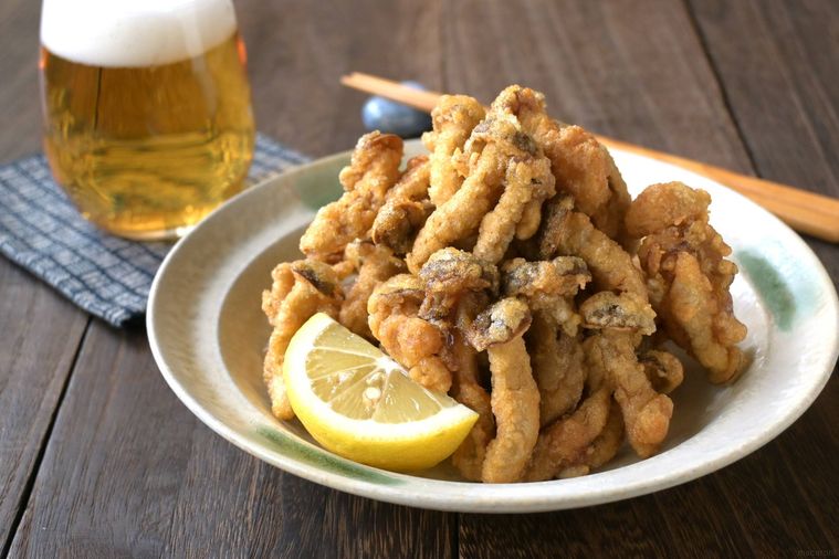 丸皿に盛り付けられたしめじのからあげの奥にビールが注がれたコップがある