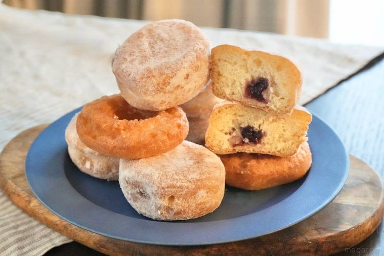 木のカッティングボードと青色の皿の上に積み上がった冷凍ドーナツ