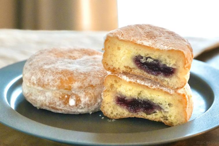 グレーの皿にのったストロベリーソース入りのシュガードーナツの断面