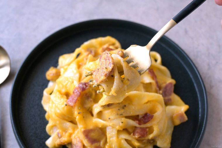 ほうとうカルボナーラの麺とベーコンをフォークで絡め取る様子