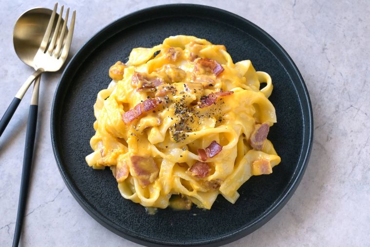 黒い丸皿に盛り付けられたほうとうカルボナーラ