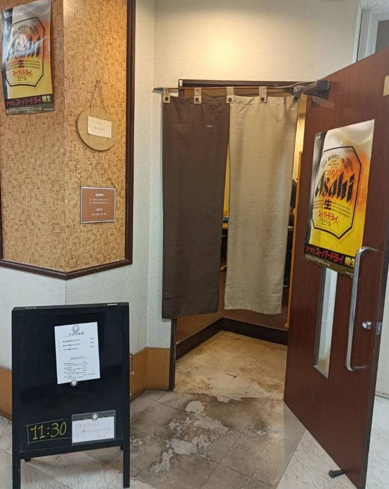 茶色のドア付近にスタンド看板がたてられたたべ処 ちゃぼんの外観