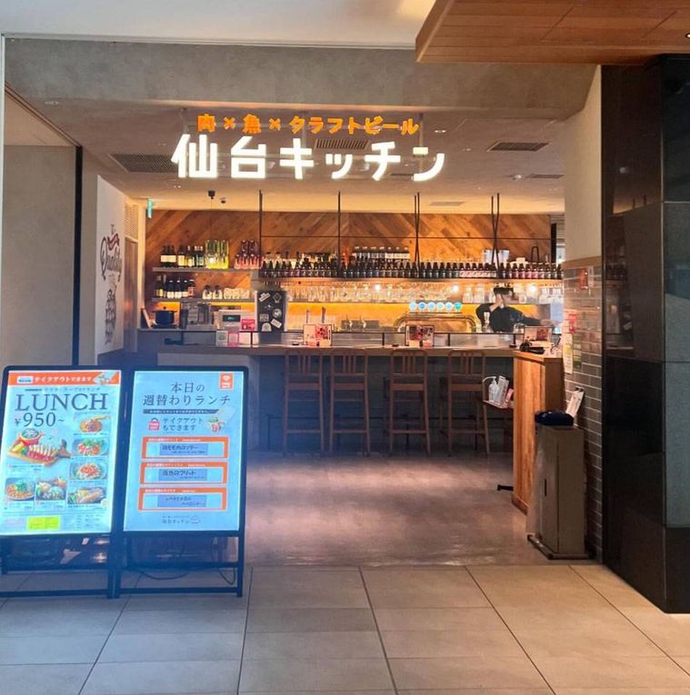 電飾の店名がかかり入り口からカウンターが見える仙台キッチンの外観