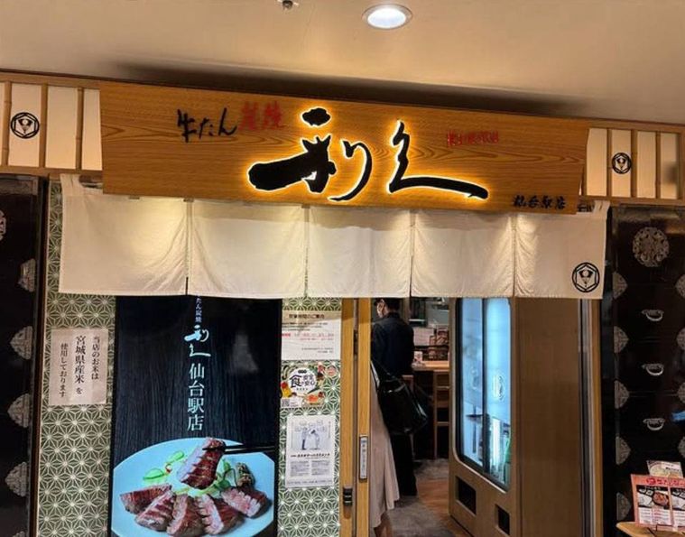 木の看板と白いのれんがかけられた牛たん炭焼 利久 仙台駅店の外観