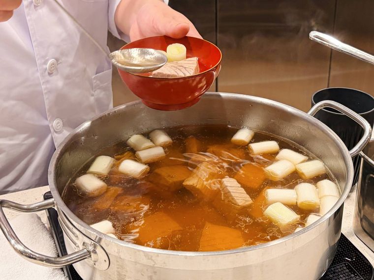 大きな鍋からおわんに汁を注ぐ様子