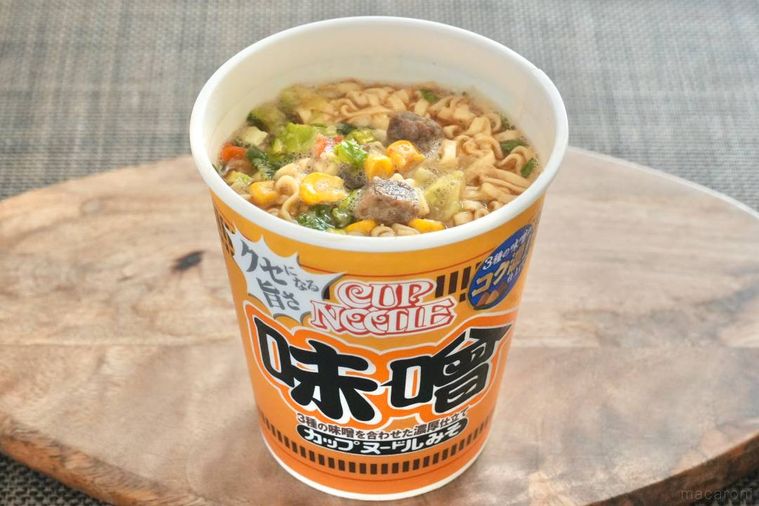 木のカッティングボードにのったオレンジ色のパッケージの味噌カップヌードル