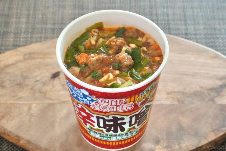 木のカッティングボードにのった赤いパッケージの辛味噌カップヌードル