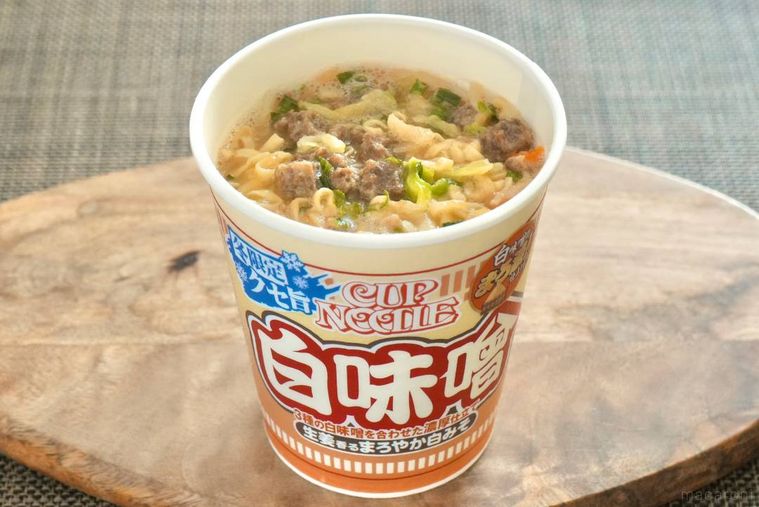 木のカッティングボードにのった赤いパッケージの辛味噌カップヌードル