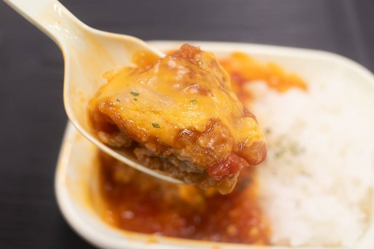 とろりチーズと卵黄ソースのトマトバーグ弁当を箸上げしている様子