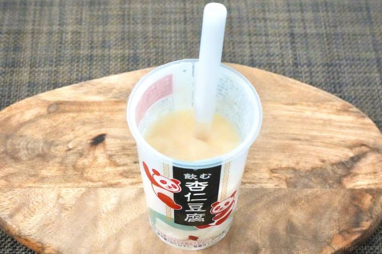 木のカッティングボードにのった飲む杏仁豆腐のドリンクカップと白いストロー