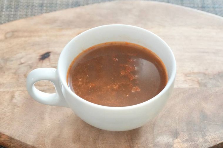 木のカッティングボードにのった白いマグカップに入った飲む麻婆豆腐