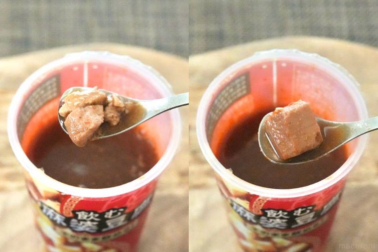 赤いカップの飲む麻婆豆腐を銀色のスプーンですくう様子