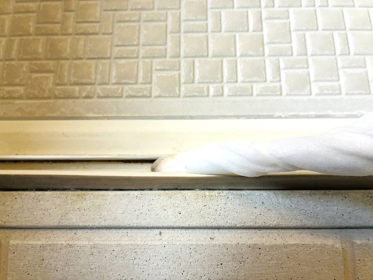 スキマ棒で浴室のドアレールを掃除している