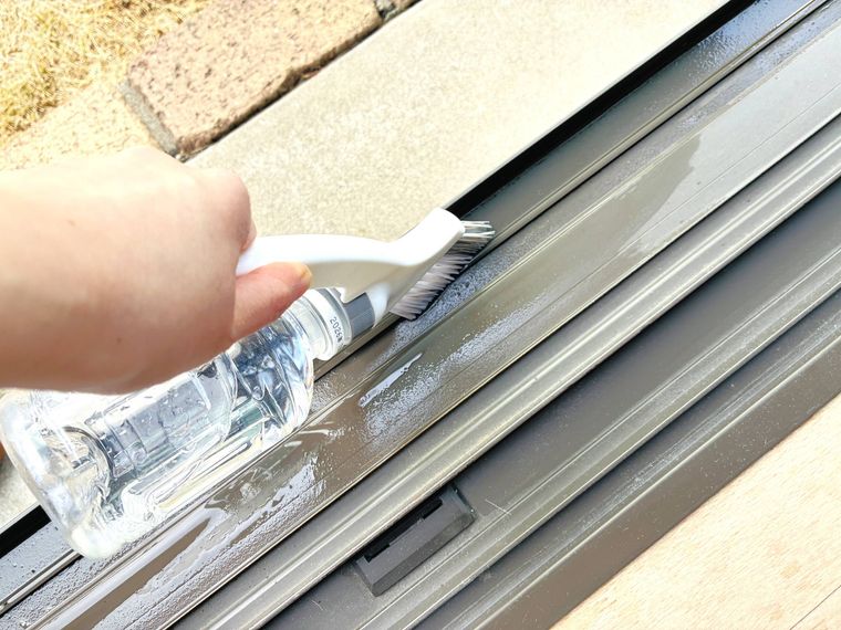 ペットボトル付きのブラシでサッシを掃除している