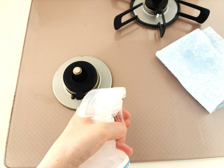 油汚れ用キッチンクリーナーをガスコンロにスプレーしている