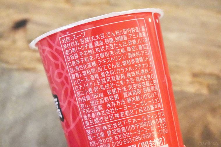 木のカッティングボードと赤いドリンクカップの原材料表示