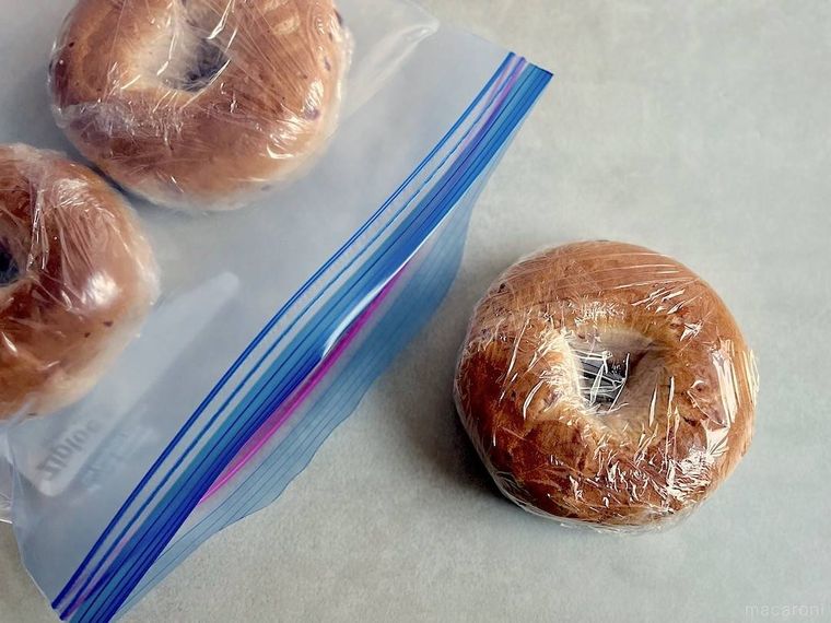 ラップで包んだコストコのベーグルを、ジップ付き保存袋へ入れているところ