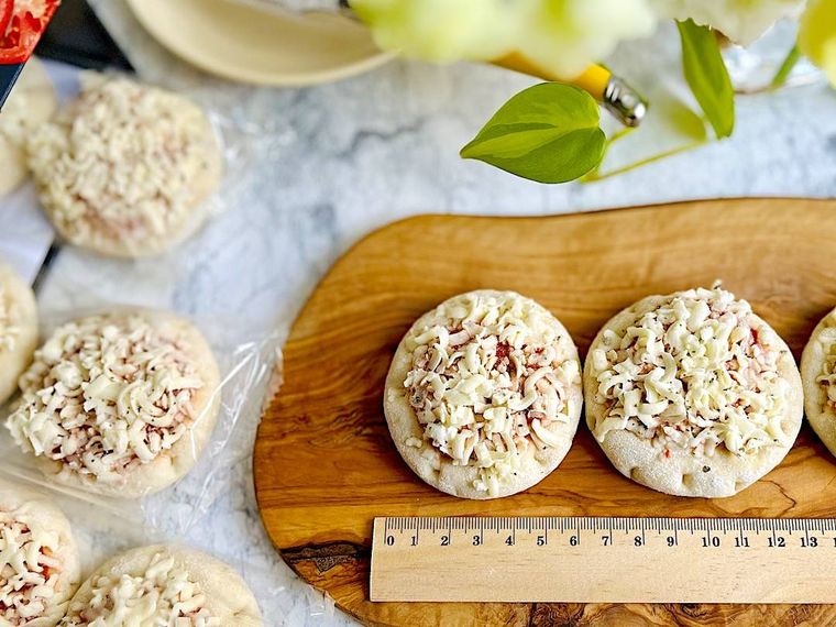 袋から出してウッドボードに2枚並べたコストコのミニピザ、定規