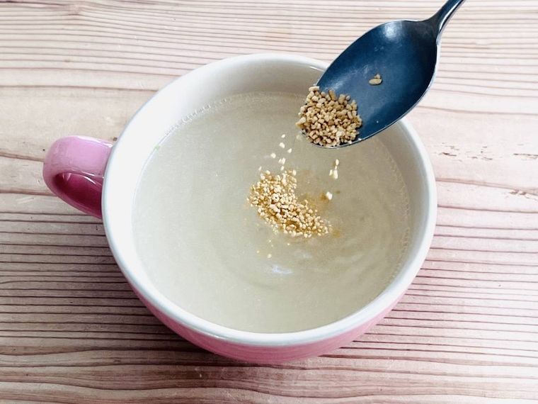 お湯が入ったスープカップにコンソメを加えている様子