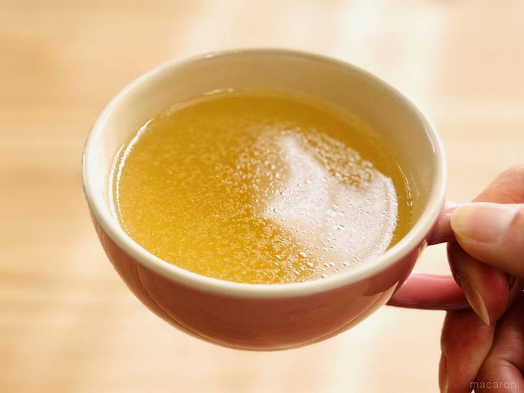 コンソメスープが入ったスープカップを持ち上げている様子