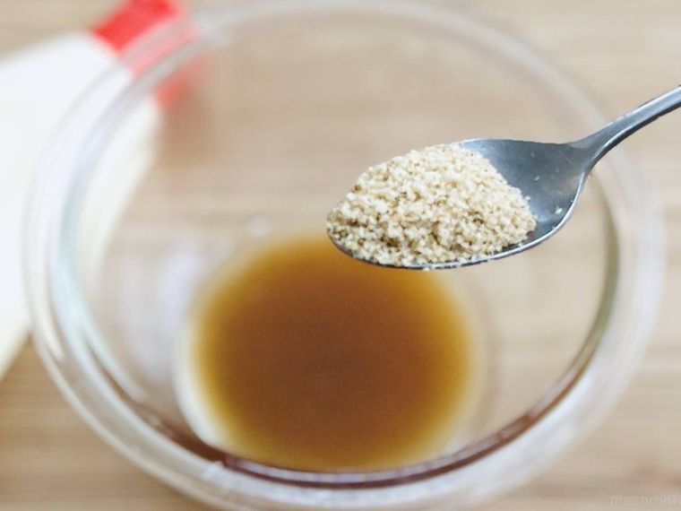 ツナ缶の油で作ったドレッシングに白すりごまを加えようとしている様子