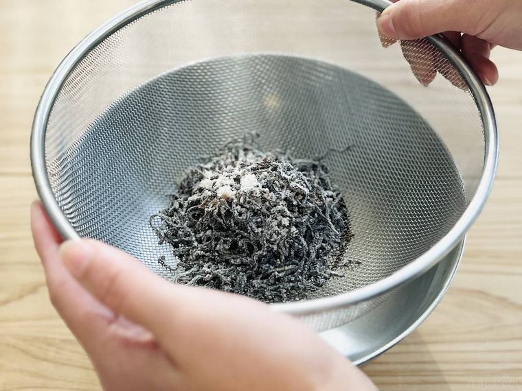 塩こんぶが入ったザルを振るっている様子