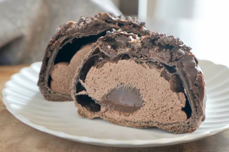 木のカッティングボードと白い皿にのったチョコレートクッキーシューの断面