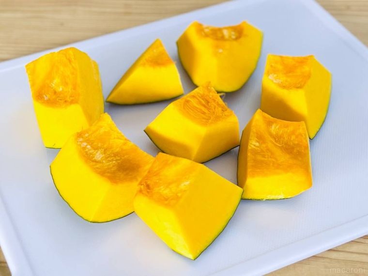 切り分けたかぼちゃが白いまな板の上に置かれている様子