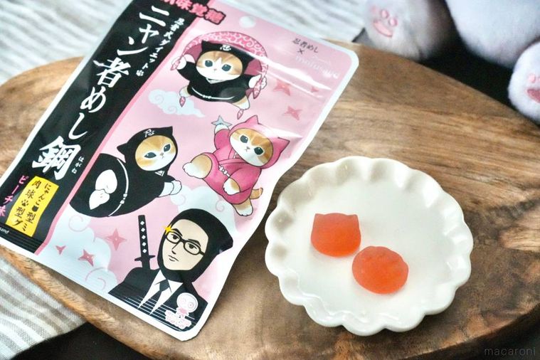 木のカッティングボードと白い皿にのった桃味のグミと忍者めしパッケージ