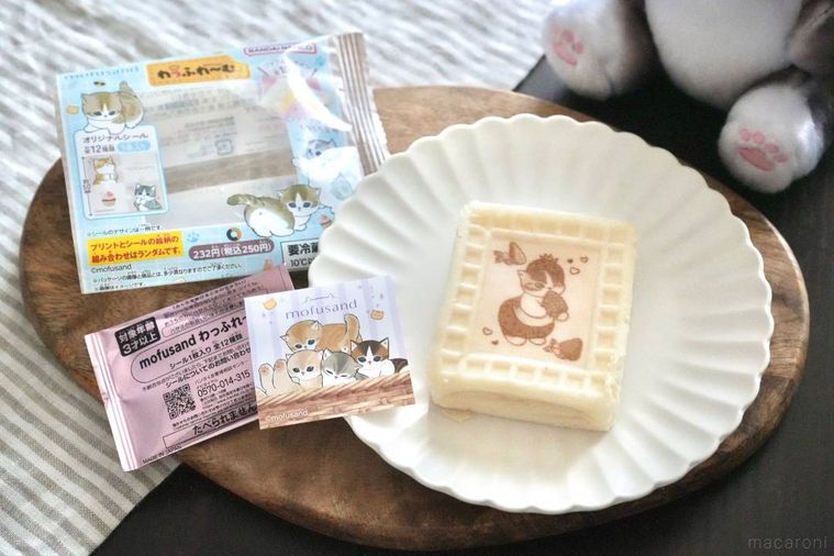 木のカッティングボードと白い皿にのった白いワッフルスイーツと猫のパッケージとシール