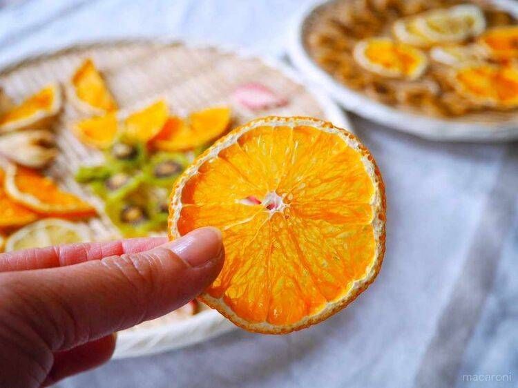 皿に盛られたドライフルーツとつまんだオレンジ